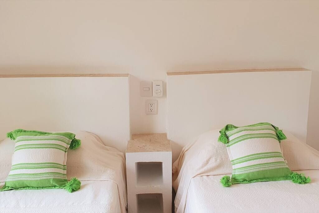 Two twin beds with green-striped pillows and a small bedside table between them.