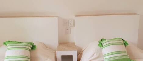 Two twin beds with green-striped pillows and a small bedside table between them.