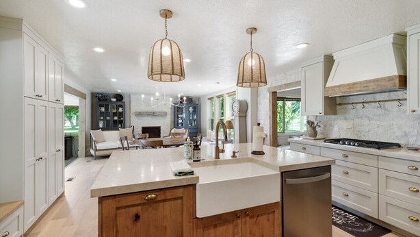 A spacious kitchen with white cabinets, a large island, and pendant lighting.