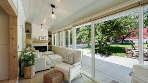 A cozy living room with a fireplace, a sofa, and a large window overlooking a garden.