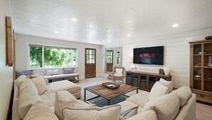 A spacious living room with a large TV, comfortable seating, and a wooden coffee table.
