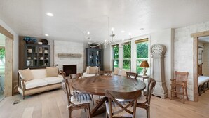 A spacious dining area with a round wooden table surrounded by chairs, a sofa, and a cabinet with glass doors.