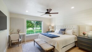 A bedroom with a bed, bedside tables, a chair, a window, and a ceiling fan.