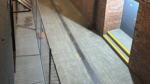 Ein schmaler Gang mit Ziegelmauern, Lichterketten und Metallgeländern.