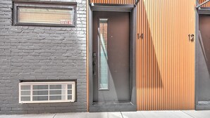 Ein modernes Gebäude mit Ziegelaußenwand, einer Metalttür und einer Holzverkleidung auf der rechten Seite.