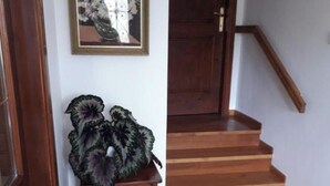 A wooden staircase with a handrail, a small wooden cabinet with a plant, and a framed picture on the wall. - Feel surrounded by nature. Pets allowed (Sežana)