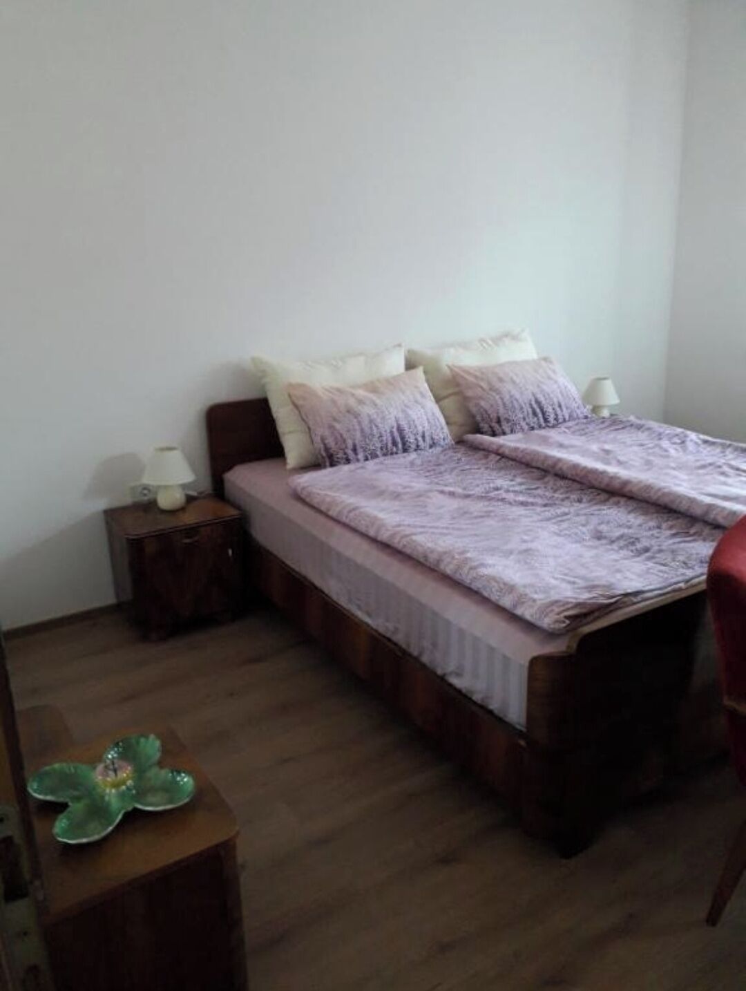 A bedroom with a bed, two bedside tables, and a small table with a green object on it.