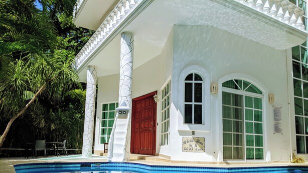 Vista da piscina de um edifício com fachada branca, janelas grandes e uma porta vermelha.