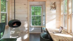 A cozy cabin interior with a fireplace, a laptop on a desk, and a deer head decoration on the wall. - Serene, Romantic Getaway, Outdoor Shower, and Hiking! (Sylva)