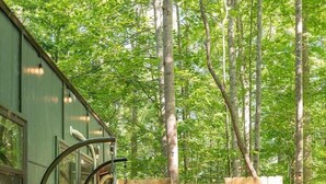 A wooden deck with a hanging chair and a small wooden structure, surrounded by trees. - Serene, Romantic Getaway, Outdoor Shower, and Hiking! (Sylva)