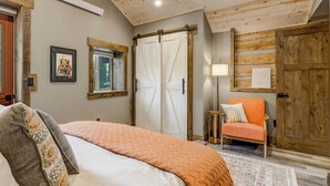 Een slaapkamer met een bed, een stoel, een raam en een kledingkast.