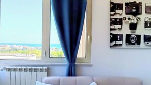 Een kamer met uitzicht op zee, een raam met gordijn, een radiator en een muur met meerdere camera's.