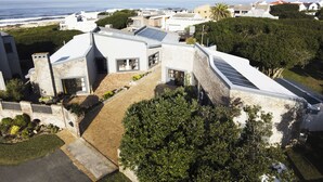 Una casa moderna con paneles solares, fachada de piedra y vista al mar.