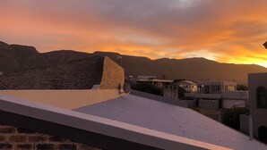 Una terraza con un muro de piedra y un edificio moderno con tejado plano.