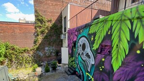 A courtyard with a mural, outdoor furniture, and a staircase.