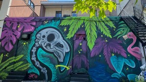 A mural with a skull and floral design on a building wall.