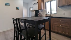 A modern kitchen with wooden cabinets, a black dining table with chairs, and a pendant light.