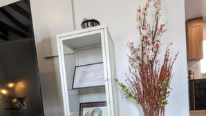A white shelving unit with framed pictures and a vase with branches and flowers.