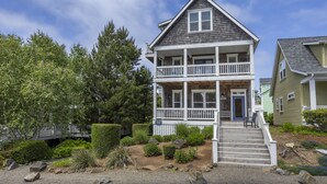 Une maison à deux étages avec un porche, une porte d’entrée et un escalier menant à l’entrée.