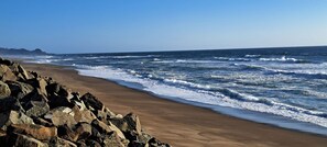 A beach with a rocky shoreline and waves crashing onto the sand.