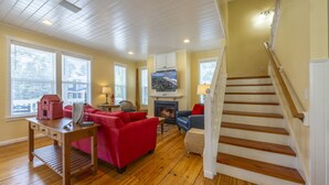 Un salon avec une cheminée, un téléviseur et un escalier.