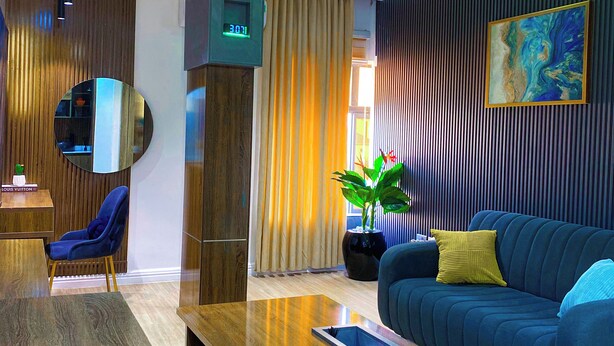 Ein modernes Wohnzimmer mit einem blauen Sofa, einem Holztisch und einem großen Spiegel.