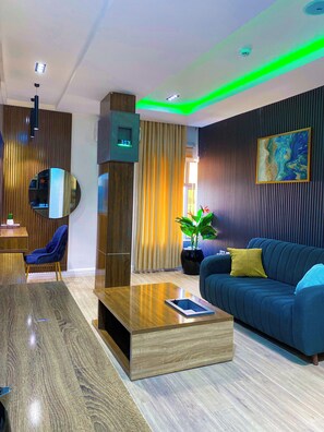 A modern living room with a blue sofa, wooden coffee table, and a large mirror.