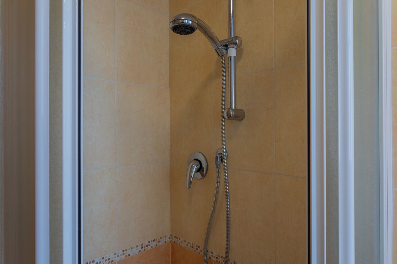 A shower with a handheld showerhead and a wall-mounted faucet.