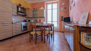 A compact kitchen with modern appliances, a dining area with wooden chairs, and a small TV on a wooden counter. - Frejus Apartment by Wonderful Italy (Turin)