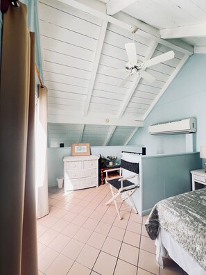 A bedroom with a sloped ceiling, a ceiling fan, a bed, a dresser, a chair, and an air conditioning unit. - 2-bed loft-style condo sleeps six, WiFi, pool, AC; walk to restaurants & beach (Frigate Bay)