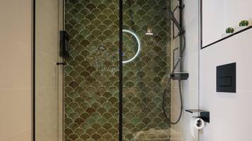 Un bagno moderno con doccia vetrata, vaso bianco e parete rivestita in piastrelle verdi.
