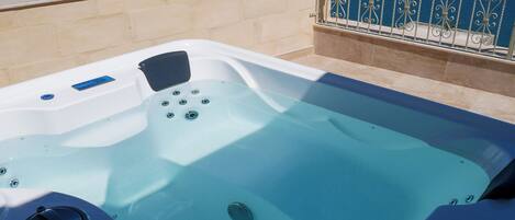 A hot tub with a clear view of the sea and a cityscape in the background.