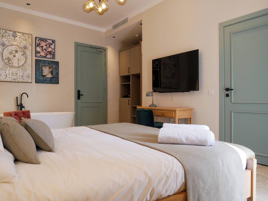 A bedroom with a bed, a desk, a television, and a wardrobe.
