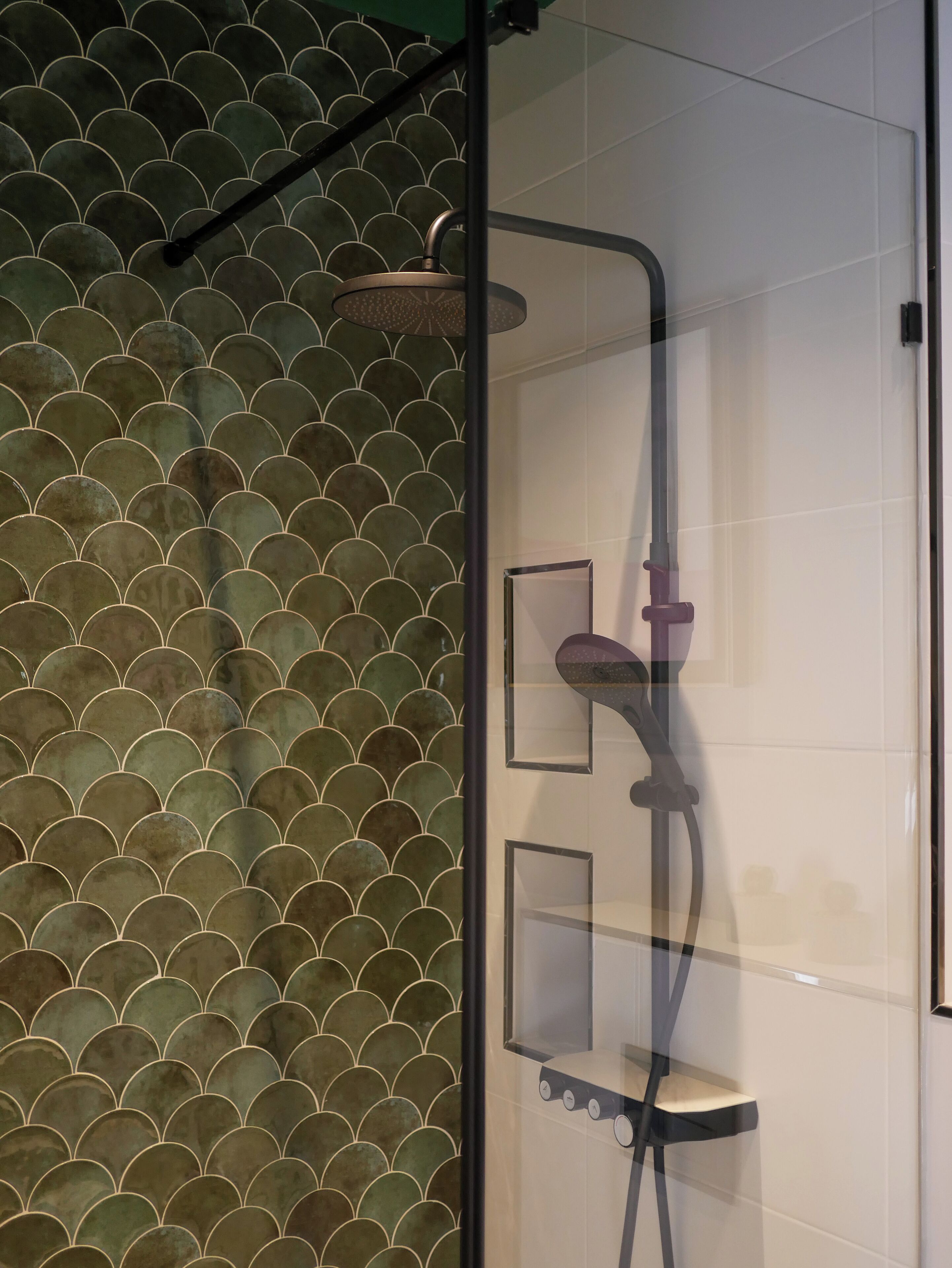 A glass-enclosed shower with a modern design, featuring a curved showerhead and a handheld shower attachment.