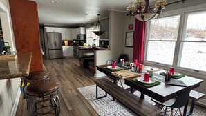 A modern kitchen with a dining area, wooden flooring, and a large window with a view of the outdoors. - the HUB - Fun Board Game 1980s Vibe @ Letchworth - 8 mins SUNY Geneseo - 3BD 2BA (Mount Morris)