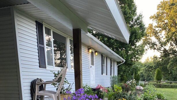 A house with a front porch, a garden with various plants and flowers, and a stone border. - the HUB - Fun Board Game 1980s Vibe @ Letchworth - 8 mins SUNY Geneseo - 3BD 2BA (Mount Morris)