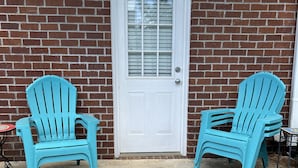 A front view of a house with a white door, two blue Adirondack chairs, and a brick wall. - Auburn First Floor Condo. Walking Distance To Jordan Hare and Auburn Arena (Auburn)