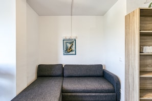 A modern room with a grey sofa, a wooden bookshelf, and a framed artwork on the wall.