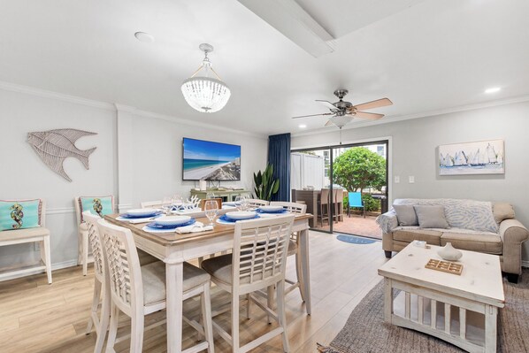 A spacious living area with a dining table set for four, a sofa, and a coffee table.