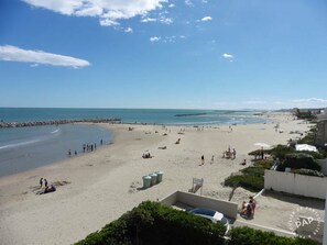 Een strand met mensen, een heldere lucht en een rustige zee.