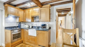 A kitchen with wooden cabinets, a stove, a sink, and a dining table. - 2 bedroom accommodation in Burgh Le Marsh (Burgh Le Marsh)