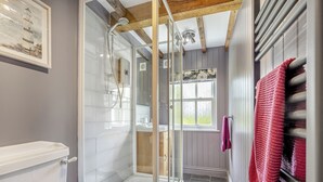 Een badkamer met een douchecabine van glas, een toilet, een wastafel en een raam met uitzicht.