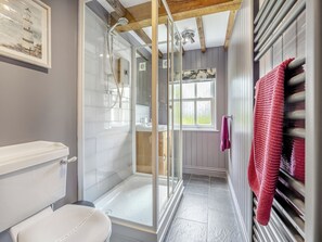 A bathroom with a glass-enclosed shower, a toilet, a sink, and a window with a view.