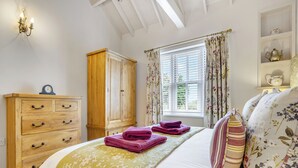 Een slaapkamer met een bed, een houten garderobe en een raam met gordijnen.