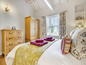 A bedroom with a bed, wooden wardrobe, and a window with curtains.