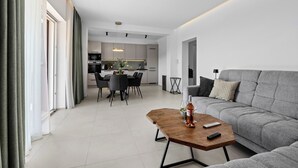 A modern living room with a grey sofa, a wooden coffee table, and a dining area with a table and chairs. - Apartment Klara - beautiful pool apartment for 7 people (Rabac)