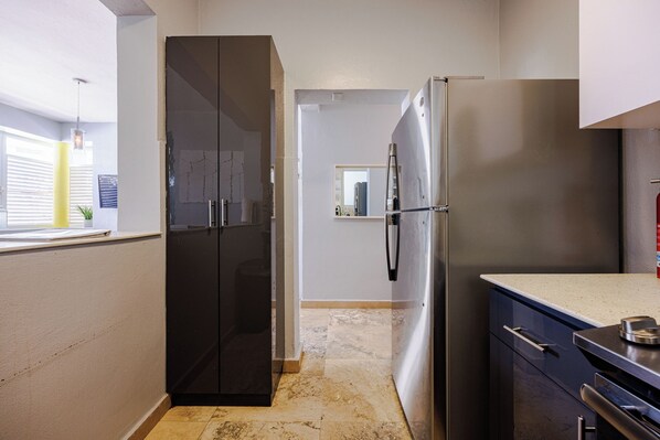 A kitchen with a black double-door refrigerator, a stainless steel fridge, and a countertop with a sink.