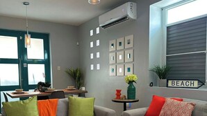 Ein modernes Wohnzimmer mit zwei grauen Sofas, einem Couchtisch und einem Essbereich mit Tisch und Stühlen.