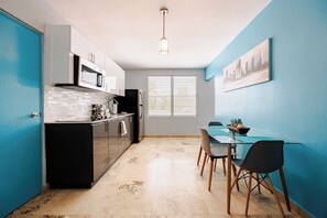 Una cocina moderna con un refrigerador negro, armarios blancos y una pared de acento azul.