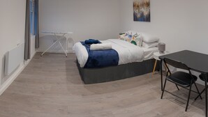 A modern bedroom with a bed, bedside table, and a desk with a chair.
